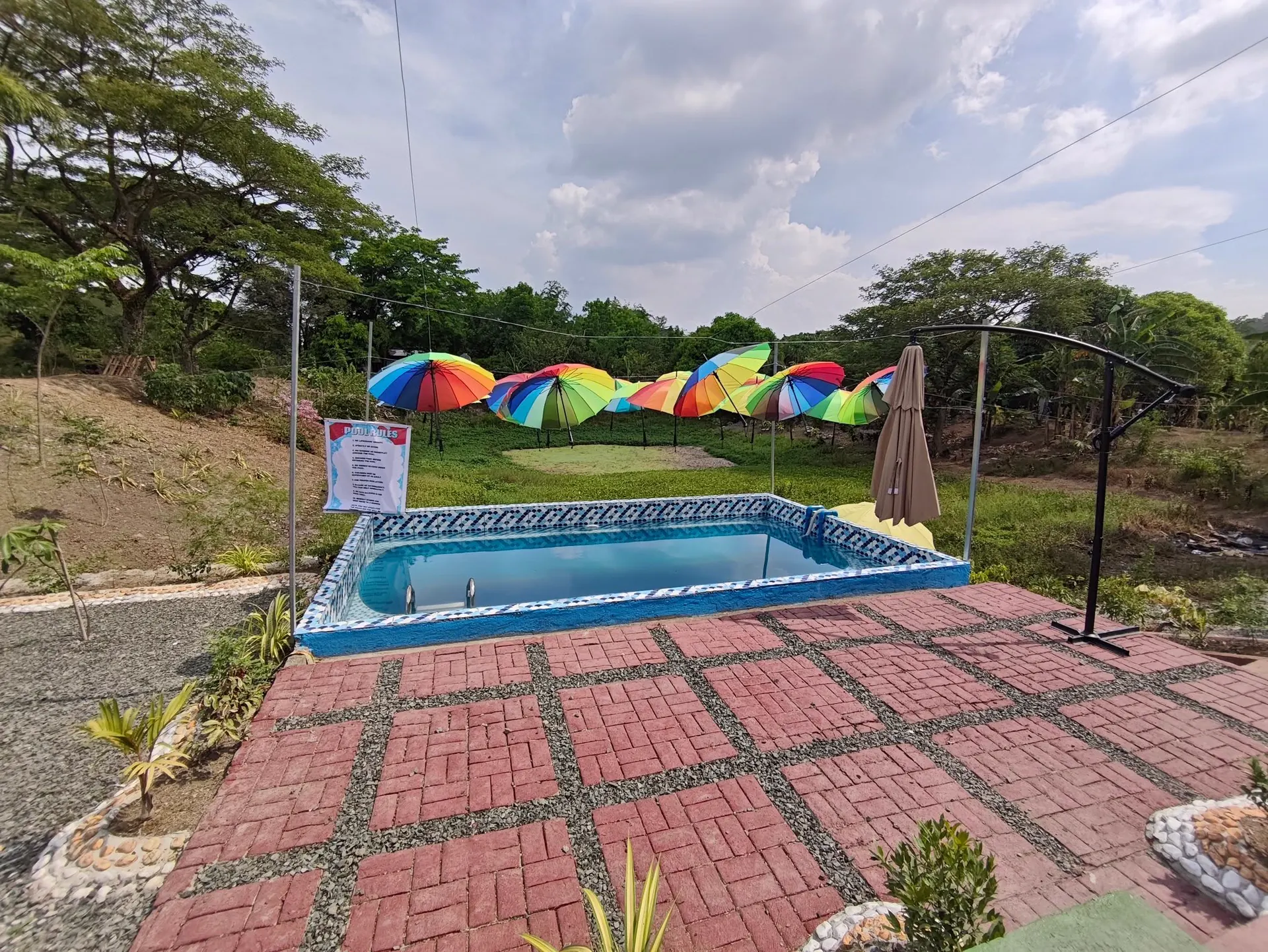 Gazebo pool ringed with rainbow parasols on a brick patio
